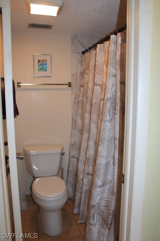 bathroom featuring toilet, a textured ceiling, and tile flooring