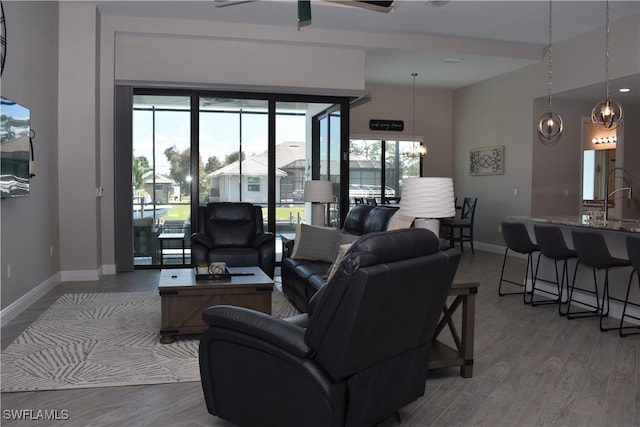 living room with sink, ceiling fan with notable chandelier, and light hardwood / wood-style floors