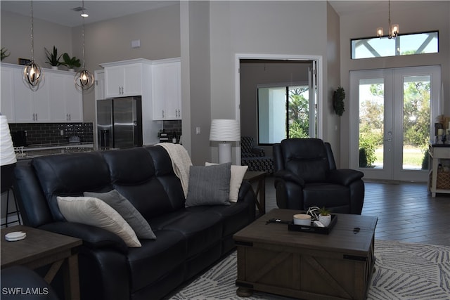 living room with a high ceiling, wood-type flooring, a chandelier, and french doors