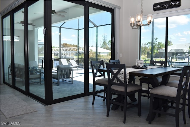 dining room with a wealth of natural light, ceiling fan with notable chandelier, and hardwood / wood-style floors