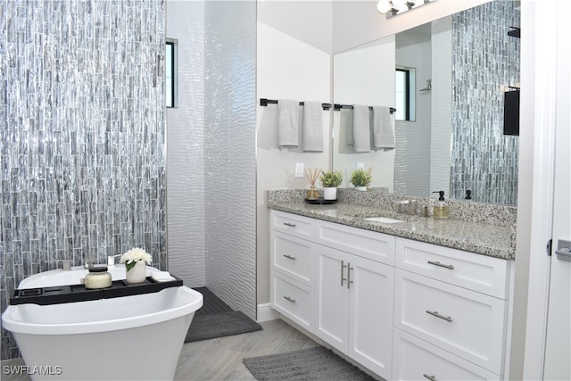 bathroom with a tub to relax in, vanity, and tile walls