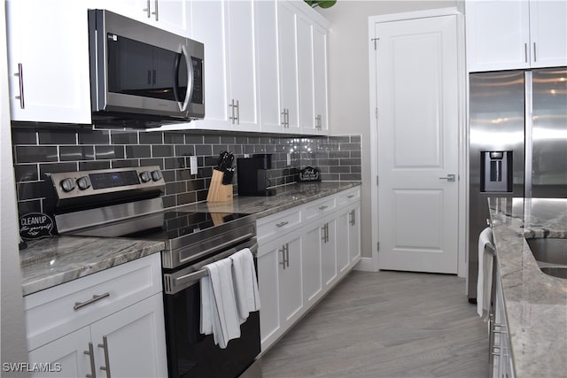 kitchen featuring light stone countertops, appliances with stainless steel finishes, light wood-type flooring, backsplash, and white cabinets