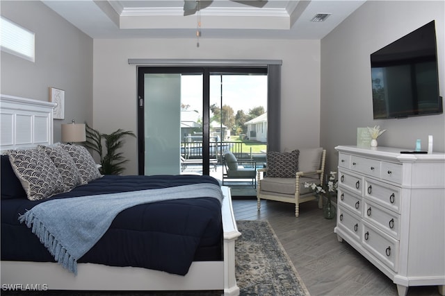 bedroom featuring crown molding, access to exterior, a tray ceiling, and dark hardwood / wood-style flooring