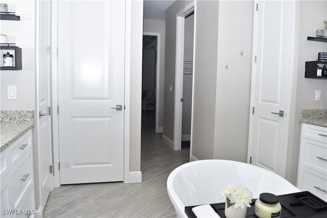 bathroom featuring vanity, a washtub, and hardwood / wood-style floors