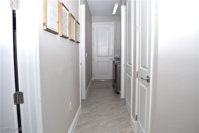 corridor with washing machine and clothes dryer and light wood-type flooring