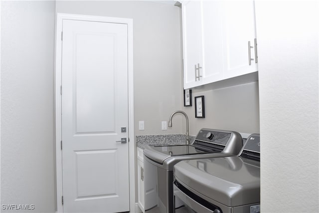 clothes washing area with cabinets and washer and dryer