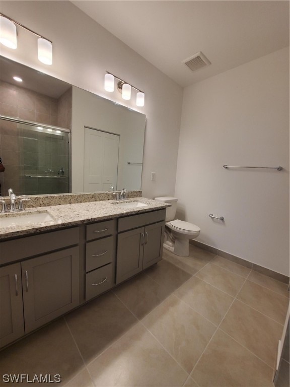 bathroom featuring tile flooring, double vanity, and toilet