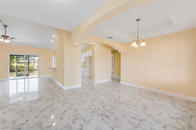 empty room featuring arched walkways, marble finish floor, baseboards, and ceiling fan with notable chandelier