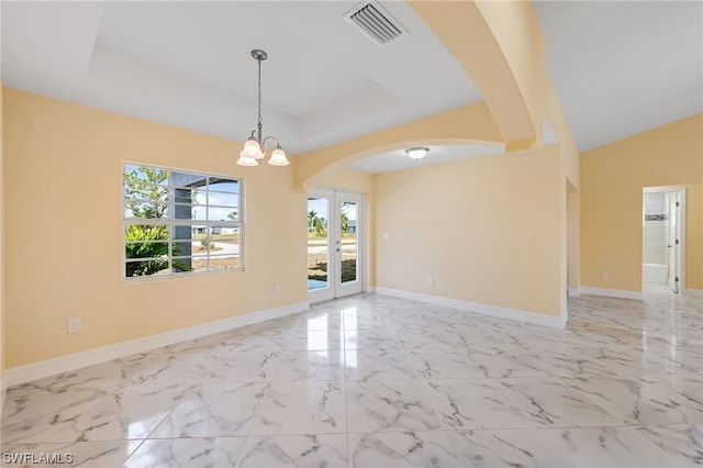 tiled spare room with a chandelier, a raised ceiling, and a wealth of natural light