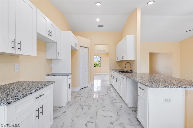 kitchen with sink, light tile floors, white cabinetry, and light stone counters