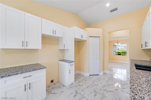 kitchen featuring lofted ceiling, light tile flooring, sink, white cabinets, and light stone counters