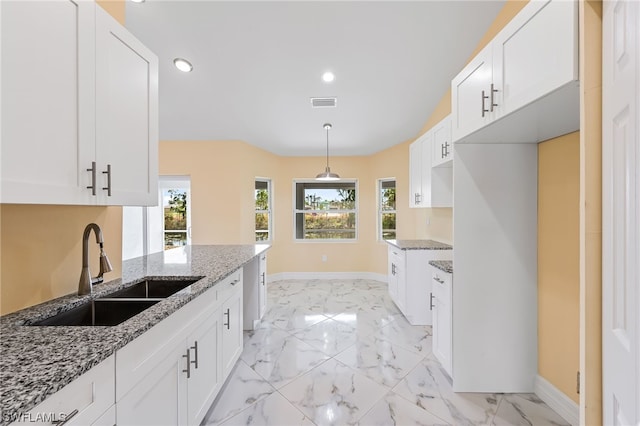 kitchen with plenty of natural light, light stone counters, and sink