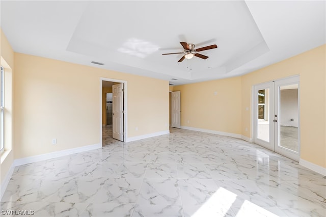 spare room with light tile floors, a tray ceiling, ceiling fan, and french doors