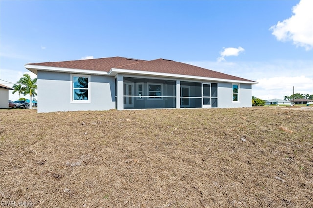 rear view of property featuring a lawn and a sunroom