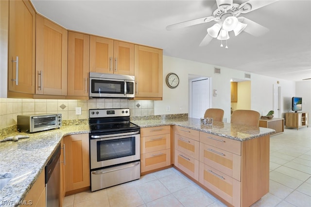 kitchen featuring kitchen peninsula, light stone countertops, backsplash, stainless steel appliances, and ceiling fan