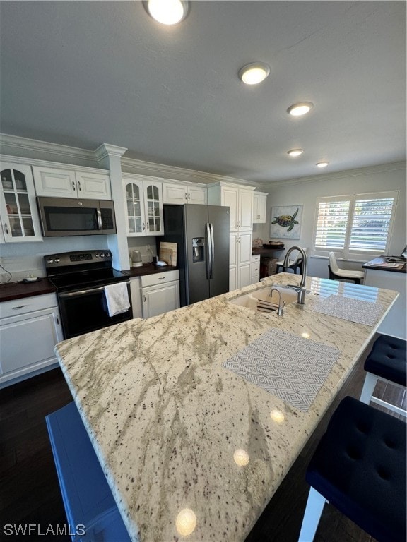 kitchen featuring a center island with sink, appliances with stainless steel finishes, white cabinetry, dark hardwood / wood-style floors, and sink