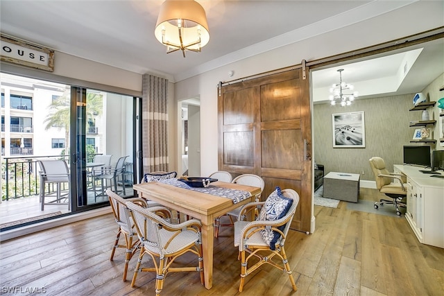 dining space featuring a barn door, a notable chandelier, and light wood-type flooring