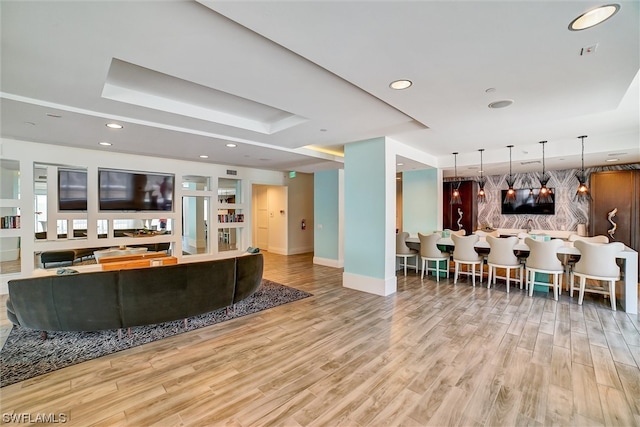 living room featuring a raised ceiling and light hardwood / wood-style floors