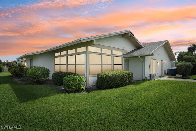 property exterior at dusk featuring a lawn