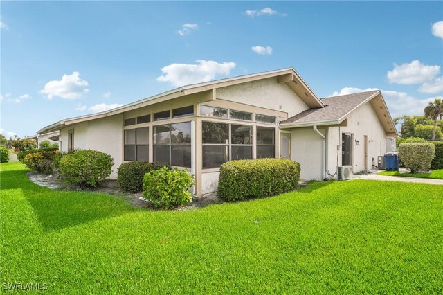 view of side of property with a sunroom, ac unit, a yard, and central air condition unit