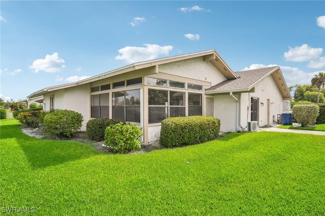 view of side of property with central AC unit, ac unit, a lawn, and a sunroom