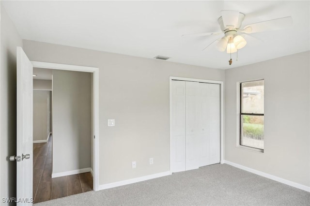 unfurnished bedroom with ceiling fan, dark carpet, and a closet