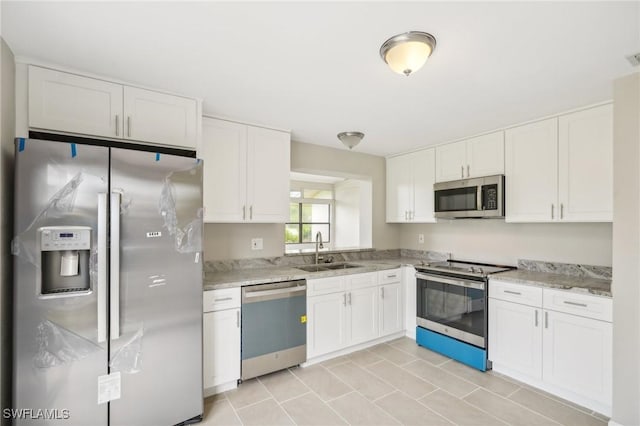 kitchen with light stone countertops, white cabinetry, sink, and appliances with stainless steel finishes