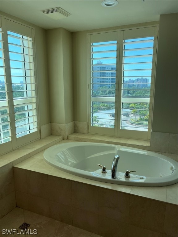 bathroom with plenty of natural light, a relaxing tiled bath, and tile flooring