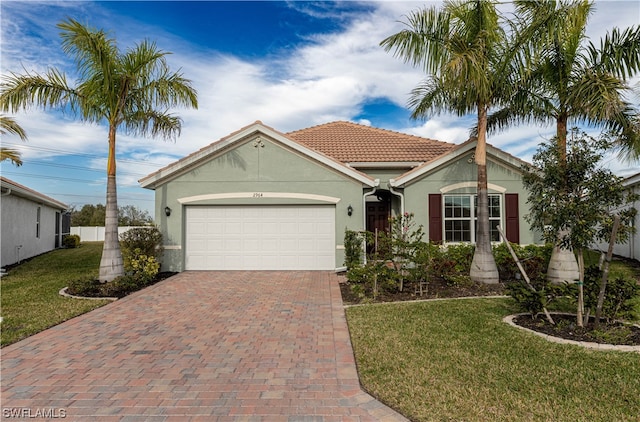 view of front of house with decorative driveway, stucco siding, an attached garage, a front yard, and fence