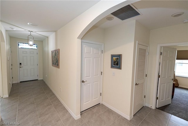 entrance foyer with arched walkways, visible vents, baseboards, and light tile patterned floors