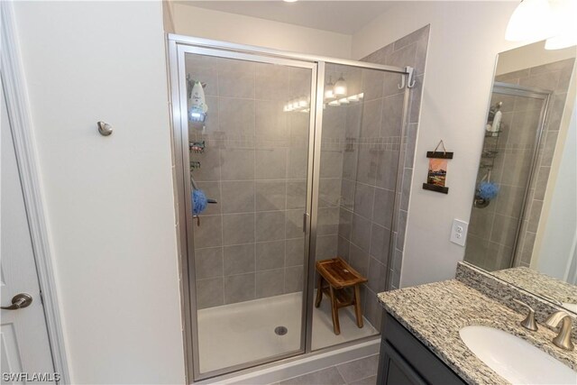 bathroom featuring a shower with shower door, vanity, and tile flooring