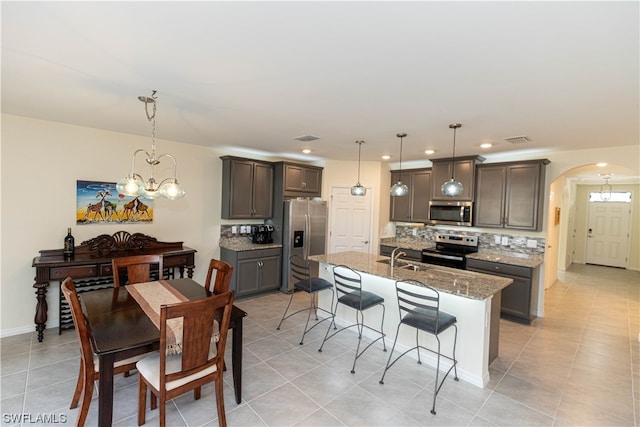 kitchen featuring a chandelier, appliances with stainless steel finishes, decorative light fixtures, and light stone counters