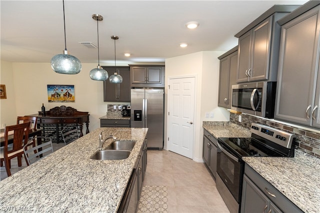 kitchen with decorative light fixtures, light stone countertops, backsplash, stainless steel appliances, and light tile floors