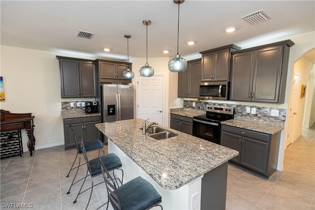 kitchen featuring a breakfast bar area, sink, stainless steel appliances, and light stone counters