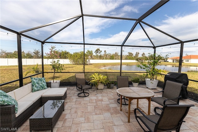 view of patio featuring glass enclosure, a water view, outdoor lounge area, and fence