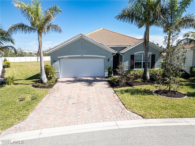 view of front facade featuring decorative driveway, stucco siding, a front yard, fence, and a garage