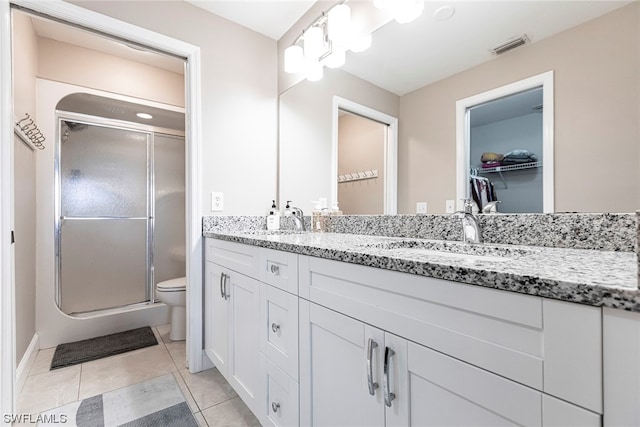 bathroom with tile patterned flooring, vanity, toilet, and walk in shower