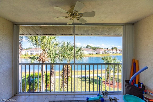 unfurnished sunroom with ceiling fan and a water view