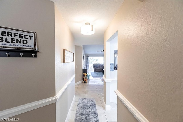 corridor featuring light tile patterned floors and a textured ceiling