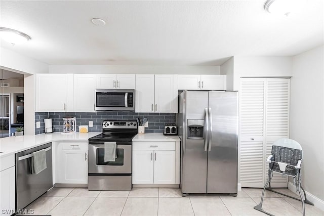 kitchen featuring appliances with stainless steel finishes, tasteful backsplash, white cabinetry, and light tile patterned flooring