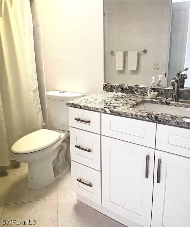 bathroom with tile flooring, large vanity, and toilet