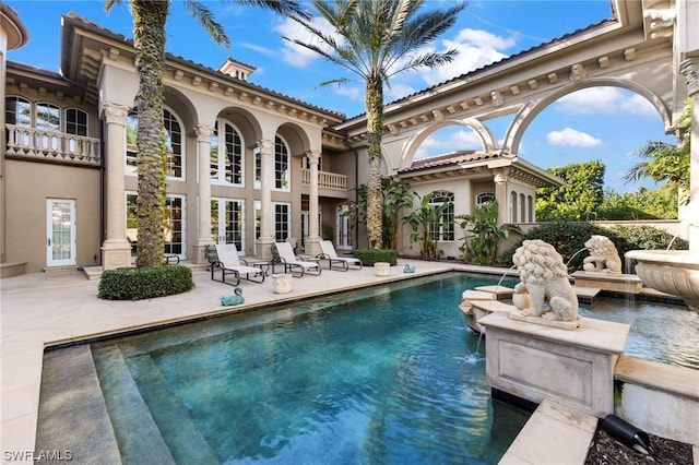 back of house featuring pool water feature, a balcony, and a patio
