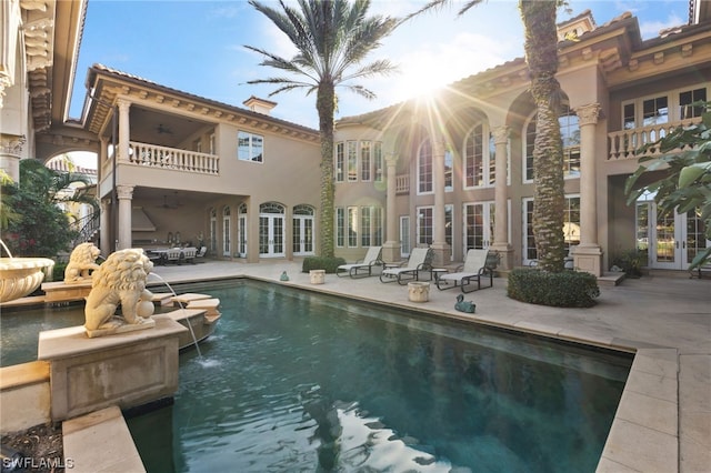 view of pool with pool water feature, french doors, ceiling fan, and a patio