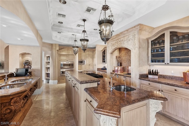 kitchen featuring pendant lighting, dark stone countertops, a spacious island, and sink