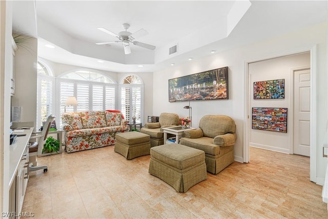 living room featuring ceiling fan and a raised ceiling