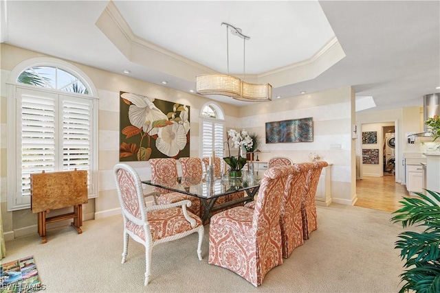 dining area with light colored carpet, crown molding, and a tray ceiling