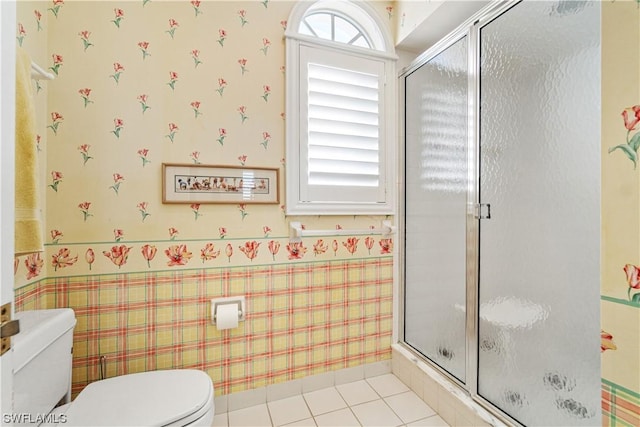 bathroom with a shower with door, toilet, and tile patterned floors