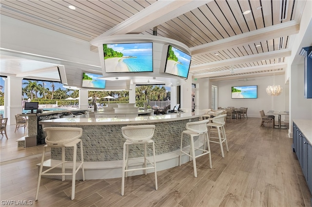 bar with stone countertops, decorative light fixtures, wood ceiling, light hardwood / wood-style floors, and beamed ceiling