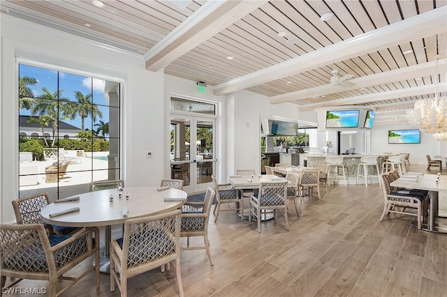 dining space featuring french doors, beamed ceiling, light hardwood / wood-style floors, a notable chandelier, and wooden ceiling