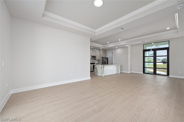 unfurnished living room featuring a raised ceiling, french doors, and ornamental molding